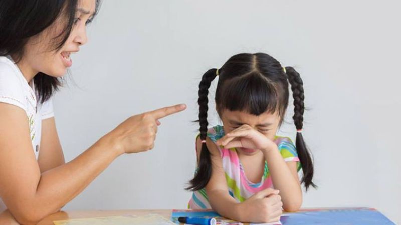 Đứng cao hơn hoặc ngồi thấp hơn chỉ tay vào mặt trẻ