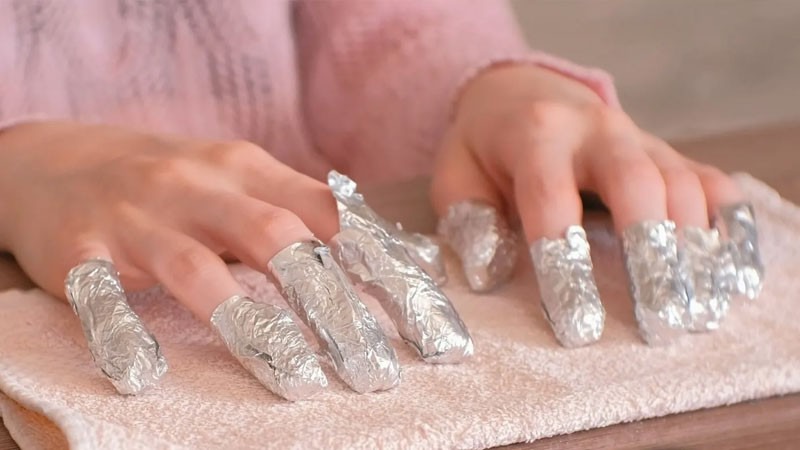 Thấm acetone vào bông gòn rồi đặt lên móng và dùng giấy bạc quấn lại